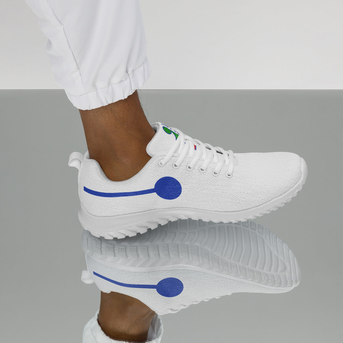 àthlon La Italia™: sneaker bianca da uomo indossata, vista laterale con “I” stilizzata blu e lacci bianchi.

