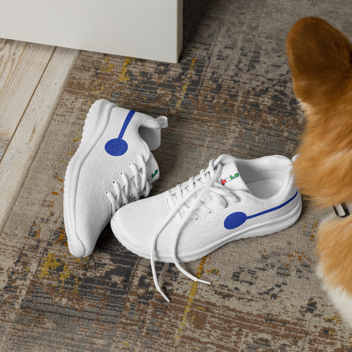 àthlon La Italia™ women's white sneakers, soft and comfortable, with blue side graphics, resting on a rug beside a dog.