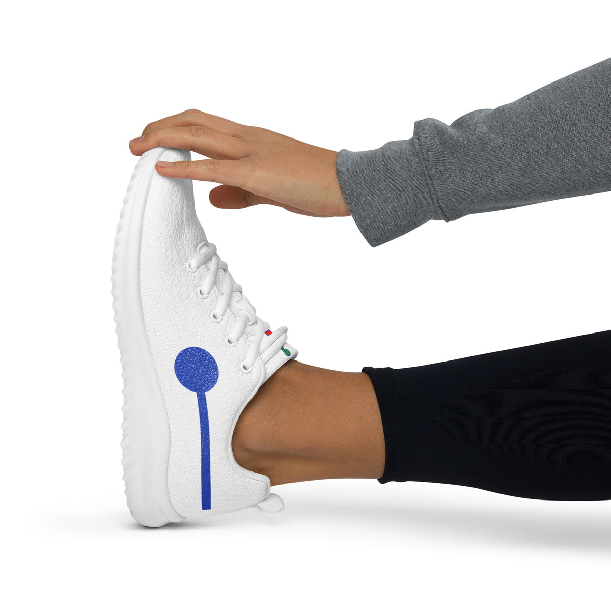 àthlon La Italia™ women's white sneaker, side view worn with black leggings, with a hand bending the toe to show excellent flexibility.
