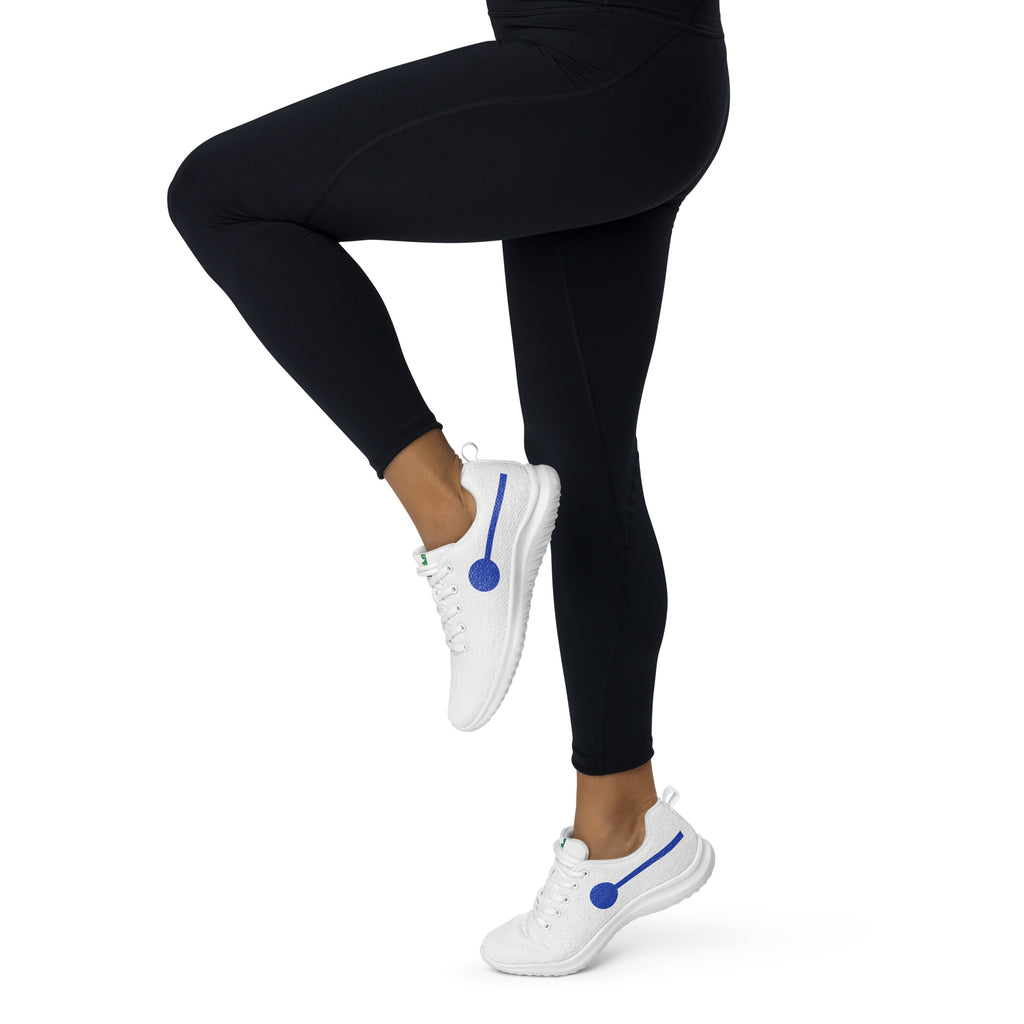 àthlon La Italia™: sneakers bianche da donna leggere e comodissime, indossate con leggings neri e una gamba sollevata.